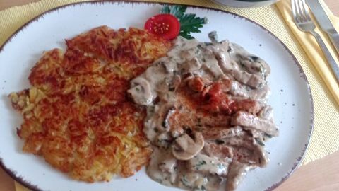 Zürcher Geschnetzeltes mit Berner Rösti: Ein klassisches Schweizer Gericht, angerichtet mit frischem Salat.