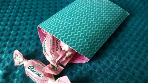 Mit dieser selbst gebastelten Geschenkverpackung aus buntem Papier werden Bonbons liebevoll und kreativ überreicht.