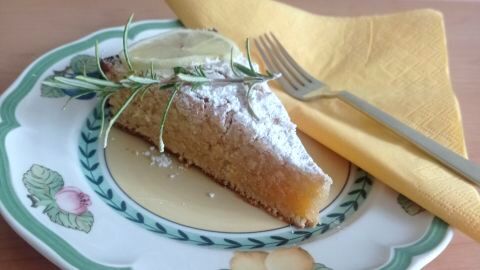 Saftige Torta Caprese al Limone: Mandel-Zitronen-Kuchen, serviert mit Puderzucker und Rosmarin.