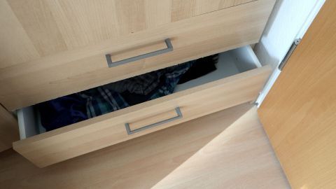 Ein offener Schrank zieht unangenehme Kleidung hervor, während die Schranktüren ungeschlossen im modernen Raum stehen.