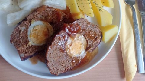 In nicht zu dünne Scheiben geschnitten, wird der Hackbraten mit Ei und Zwiebelsoße angerichtet.