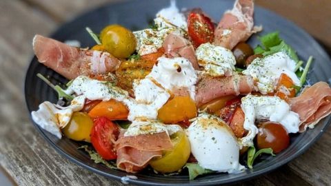 Fruchtiger Wildkräutersalat: Bunte Tomaten, Wildkräuter, Burrata und Schinken sorgen für Genuss und Vitamine auf deinem Teller.