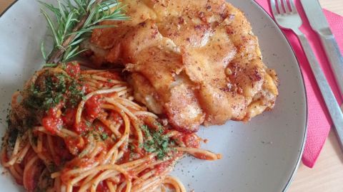 Angerichtet wird die Piccata Milanese auf vorgewärmten Tellern mit den in der Tomatensoße gemischten Spaghetti.