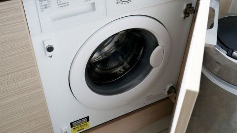 Eine Waschmaschine steht geöffnet in einer modernen Küche, bereit für den Umzug, um Wäsche zu reinigen.