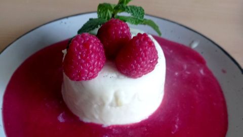So sieht Panna cotta auf Himbeerspiegel aus dem Rezept aus: cremig gest&uuml;rzt, auf Himbeersauce, mit frischen Himbeeren und Minze.