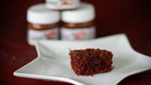 Eine kleine Portion Nutella-Schnitten liegt auf einem Teller, während im Hintergrund mehrere Nutella-Gläser sichtbar sind.