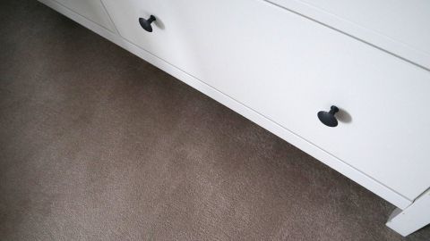 Schränke auf Teppich zu verschieben ist schwer. Mithilfe von Essstäbchen kann es gut gelingen. Probier's aus. Ein weißer Schrank mit schwarzen Griffen wird auf einem Teppich mithilfe von Essstäbchen verschoben, um den Boden schonend zu behandeln.