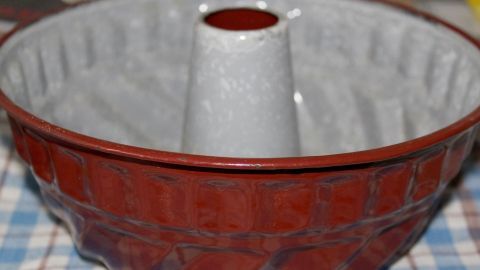 Eine elegante Backform steht auf einem karierten Tisch, bereit, leicht eingefettet zu werden, um einen gleichmäßigen Kuchen zu backen.