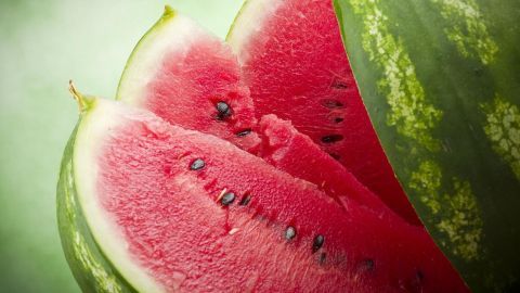 Wassermelone, in Scheiben geschnitten, mit dunkelgrüner Schale und roten Kernen. Frisches Fruchtfleisch im Sommerkontext.