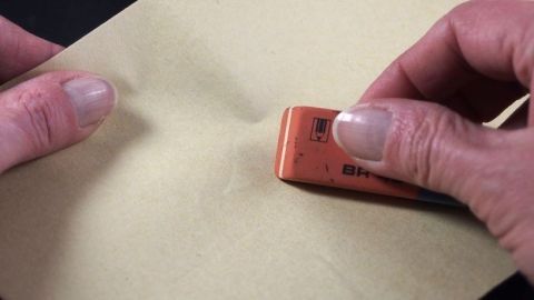 Einen verschmutzten Radiergummi kann man mit Löschpapier säubern. Ein Radiergummi wird über ein Blatt Löschpapier bewegt, um dessen Oberfläche zu säubern.