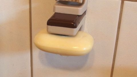 Ein Seifenstück liegt auf einem Seifenhalter im Badezimmer, bereit zur Verwendung, um es trocken zu halten.