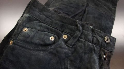 Dunkle Wildlederhose liegt ordentlich gefaltet auf einem hellen Hintergrund, bereit zur Reinigung oder Pflege.