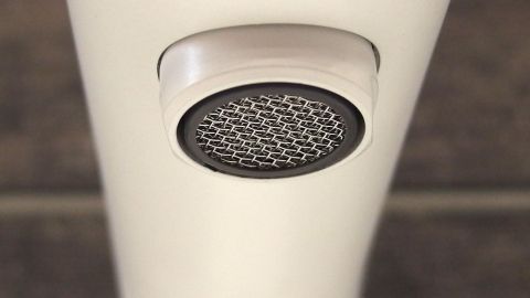 Ein Wasserhahnsiebträger, der entkalkt wird, hängt unter einem modernen Wasserhahn in einer hellen Küchenszene.