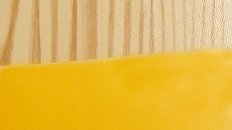 Ein Holzschrank wird mit gelber Klebefolie beklebt, um ihm ein neues, frisches Aussehen zu geben.