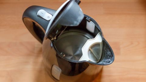 Ein Wasserkocher steht auf einem Holztisch, geöffnet, bereit zum Erhitzen von Wasser, um Kalkablagerungen zu vermeiden.