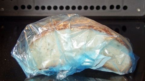 Ein Brot liegt in einer durchsichtigen Plastiktüte in der Mikrowelle, um es frisch zu halten und vor dem Austrocknen zu schützen.