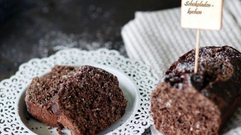 Ein saftiger Schokokuchen liegt auf einem dekorativen Teller und wird durch eine Zutatenschilderung in einem rustikalen Setting präsentiert.