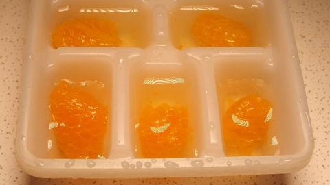 Ganz tolle Eiswürfel aus den unterschiedlichsten Früchten: viel besser als diese ollen durchsichtigen Wasserklumpen. Eiswürfel mit Fruchtstücken sind in einem Eiswürfelfach auf einer hellen Arbeitsfläche gefroren.