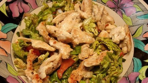 Saftiges Hähnchenfilet liegt auf einem bunten Salatbett, bereit für das Grillen in einer ansprechenden Schüssel.