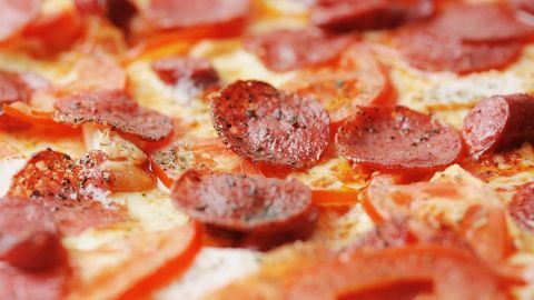 Ein Pizzateig aus Ciabatta-Brotmischung wird belegt mit saftigen Tomatenscheiben und würzigem Salami.