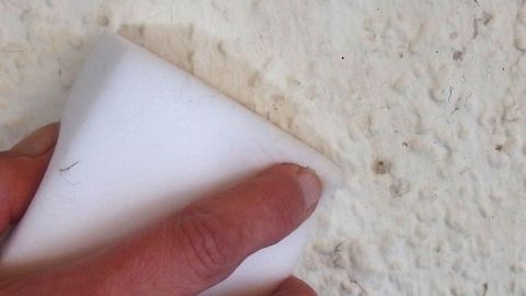 Ein Schmutzradierer reinigt mühelos eine rauhe Wandoberfläche, um Farbe und Flecken zu entfernen.