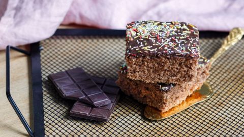 Ein saftiger Nusskuchen liegt auf einem Gitter, während neben ihm Schokoladentafeln in einem gemütlichen Umfeld liegen.