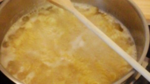 Ein Topf mit kochendem Wasser und Kartoffeln, in dem ein Kochlöffel liegt, um Überkochen zu verhindern.
