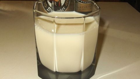 Ein Glas Milch steht auf einem Tisch, umgeben von weitem Ambiente, als Lösung gegen die Sorgen nach einer Party.
