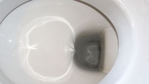 Ein WC mit klarem Wasser und einer schmutzigen Ecke, die auf eine Reinigung mit kochendem Wasser hinweist.