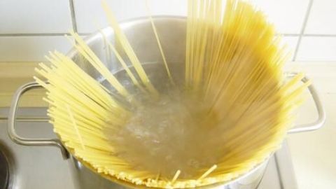 Spaghetti werden vorsichtig in kochendes Wasser in einem Edelstahltopf gegeben, um sie gleichmäßig zu garen.