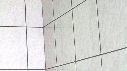 Saubere Fliesen sind an einer Wand sichtbar, zeigen klare Linien und reflektieren Licht in einem modernen Badezimmer.