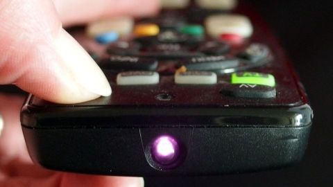 Eine Hand hält eine Fernbedienung, während sie die Funktionsüberprüfung durch den leuchtenden Infrarotstrahl testet.