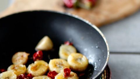 In einer Pfanne braten geschnittene Bananen mit roten Chilis, um eine scharfe und süße Kombination zu kreieren.