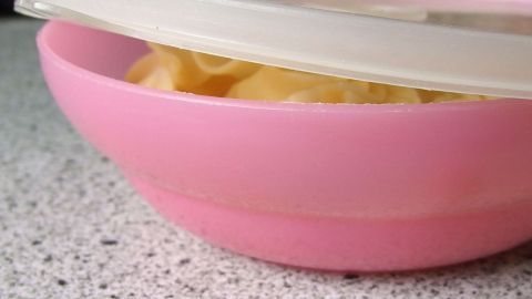 Ein häufiges Problem: Der Deckel der Frischhaltedose sitzt nicht richtig. Der Tipp im Artikel zeigt, wie du den Deckel deines rosa Behälters mit einem einfachen Trick anpassen kannst, indem du die Hitze nutzt. Eine rosa Frischhaltedose mit unpassendem Deckel sitzt schief auf einem Küchentisch, der Macaroni enthält.