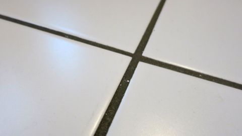 Ganz einfach, ohne Putzmittel: Mit einer Dampfente lassen sich Fugen kinderleicht reinigen. Weißer Fliesenboden mit schmutzigen Fugen, die gereinigt werden, um eine saubere Umgebung zu schaffen.