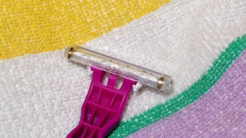 Ein Rasierer liegt auf einem bunten Handtuch und wartet darauf, verwendet zu werden, möglicherweise nach der (Intim-)Rasur.