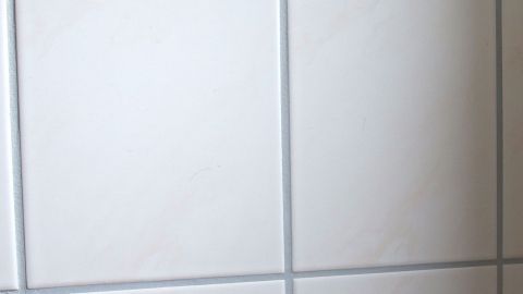 Mit einer Mischung aus Buttermilch, etwas Essig und Salz Badezimmerfliesen, Badewanne und Spülstein reinigen. Helle Badezimmerfliesen sind an der Wand verlegt, um eine saubere, moderne Umgebung im Badezimmer zu schaffen.