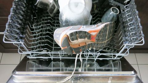 Ein Paar Turnschuhe liegt in der Spülmaschine, während Wasser und Seife sie reinigen, um sie frisch zu halten.