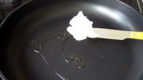Etwas Olivenöl in die Pfanne zur Butter geben, dann brennt diese nicht schwarz an. Eine Pfanne mit etwas Öl zeigt einen Klecks Butter, der darauf wartet, beim Braten nicht anzubrennen.