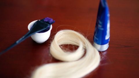 Blondierte Haare liegen neben einer Haarfarbe und einem Pinsel auf einem Tisch, bereit zur Anwendung gegen den Gelbstich.