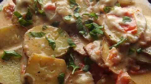 Eine herzliche Mozzarella Pfanne aus gebratenem Gemüse und Kartoffeln, garniert mit frischen Kräutern und Käse.