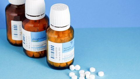 Drei Flaschen mit Zinktabletten stehen auf einem blauen Hintergrund, umgeben von weißen, runden Tabletten.
