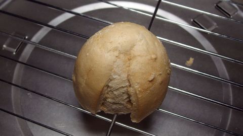 Ein trockenes Br&ouml;tchen liegt auf einem Grillrost und wird verwendet, um den verkrusteten Grillrost zu reinigen.