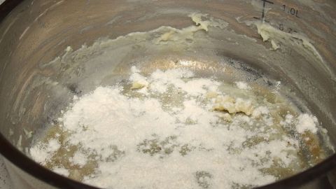 Angebranntes in Töpfen mit Backpulver und Schwamm lösen. Im Topf befinden sich angebrannte Rückstände, während Backpulver zur Reinigung bereitsteht.