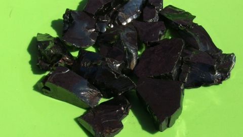 Veralgte Aquariumsteine für einen Tag in die pralle Sonne legen und schon erstrahlen sie wieder weiß! Schwarze Aquariumsteine liegen auf grünem Untergrund in der Sonne, um gereinigt und aufgehellt zu werden.