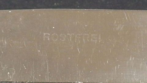 Ein Besteckstück liegt auf einem dunklen Hintergrund, mit der gravierten Aufschrift „Rustfrei“ sichtbar, was auf Spülmaschinenfestigkeit hinweist.