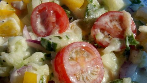 Frischer Salat mit Tomaten, Paprika und Gurke wird in einer Schüssel serviert, ideal für eine schnelle, gesunde Mahlzeit.