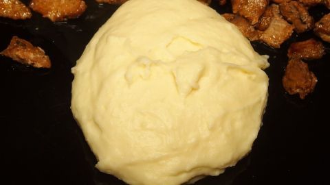 Ein cremiger Haufen Kartoffelpüree liegt in der Mitte, umgeben von knusprigen, gebratenen Kartoffelstückchen.