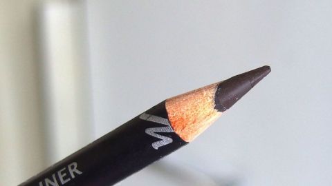 Ein Kajalstift bricht beim Spitzen nicht mehr ab, wenn man ihn vorher für ein paar Minuten ins Eisfach legt. Ein schwarzer Kajalstift mit spitzem Ende liegt vor einer hellen, unscharfen Hintergrundfläche und ist bereit zum Benutzen.