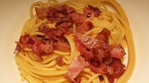 Eine Schüssel Specknudeln, in der sich gekochte Pasta mit knusprig gebratenem Speck vermischt und appetitlich anrichtet.